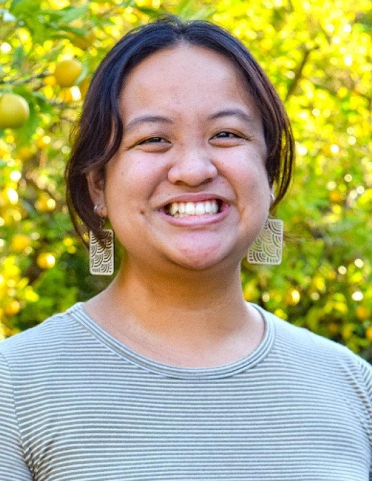 Malaya Caligtan Tran poses in front of Pitzer's orange groves